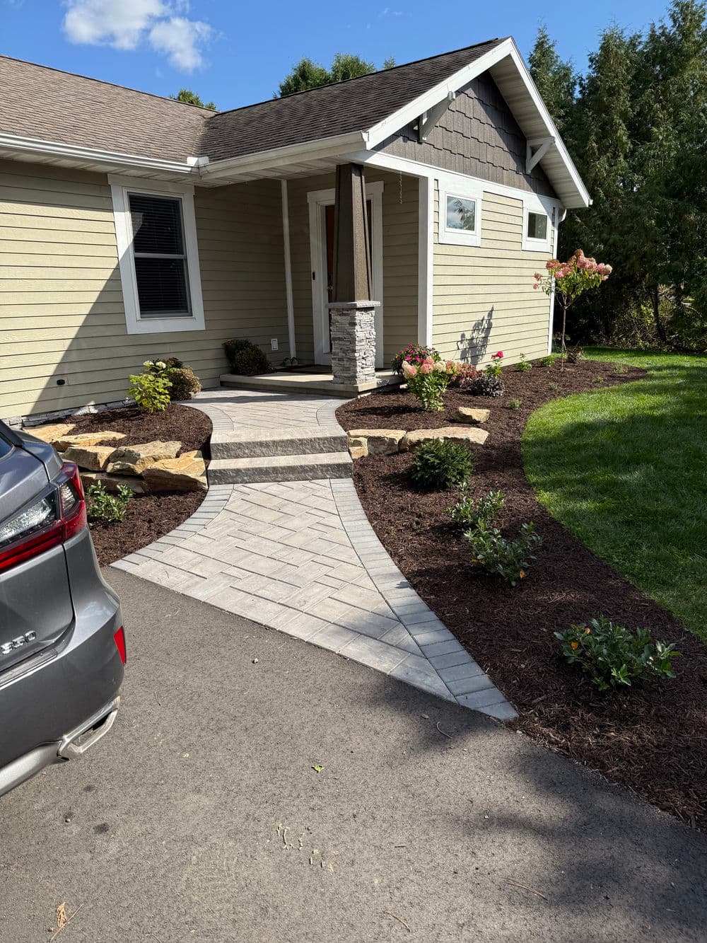 Beautifully landscaped house entrance with stone walkway and well-maintained flower beds.